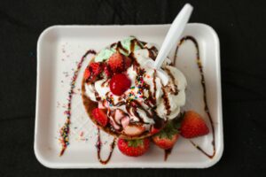 Colorful ice cream sundae topped with strawberries, whipped cream, and sprinkles.
